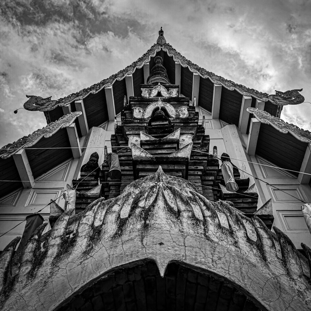 A black and white low angle shot of the ornate entrance to a temple